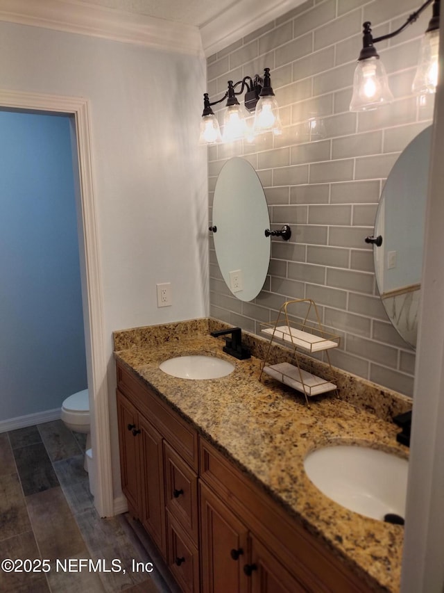 full bathroom featuring double vanity, toilet, backsplash, and a sink