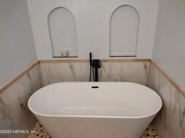 interior details featuring a freestanding tub and wainscoting