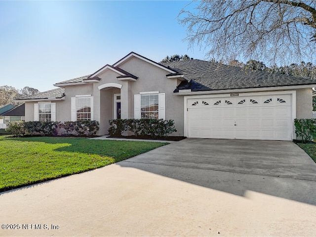 view of front of property with stucco siding, concrete driveway, a garage, and a front yard