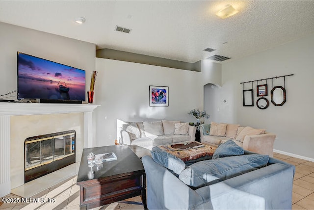 living room with tile patterned floors, visible vents, arched walkways, and a textured ceiling