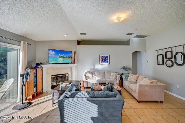 living area featuring light tile patterned floors, visible vents, arched walkways, and a fireplace