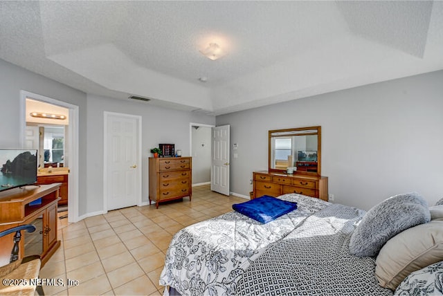 bedroom with a raised ceiling, light tile patterned floors, visible vents, and a textured ceiling