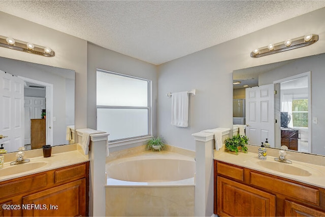 bathroom featuring a sink, a garden tub, and two vanities