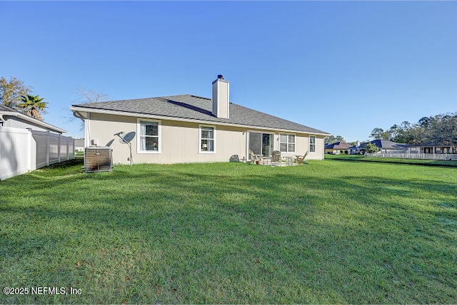 rear view of property featuring a lawn, a chimney, and fence