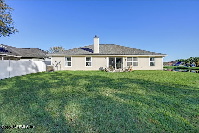 back of property with a yard, fence, and a chimney