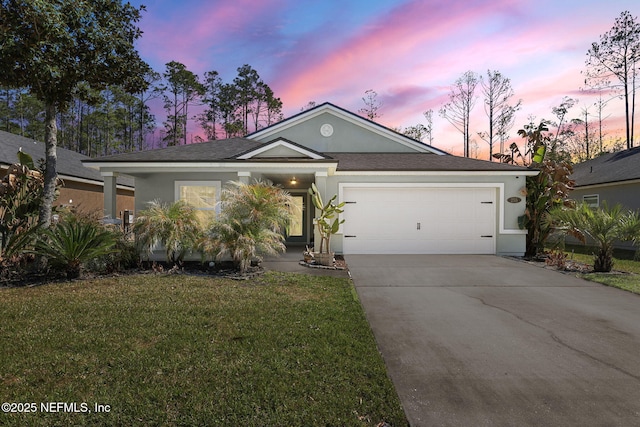 ranch-style home with roof with shingles, driveway, a yard, stucco siding, and a garage