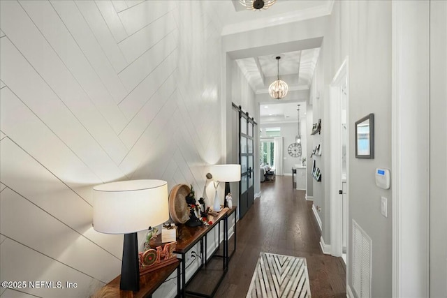 hallway featuring wood finished floors, baseboards, visible vents, ornamental molding, and a barn door