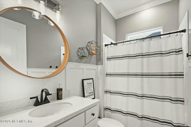 bathroom featuring a wainscoted wall, toilet, ornamental molding, a shower with curtain, and vanity