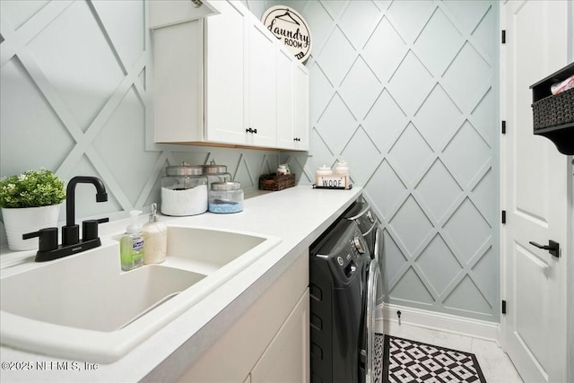 laundry area featuring a sink, a decorative wall, cabinet space, and washing machine and clothes dryer