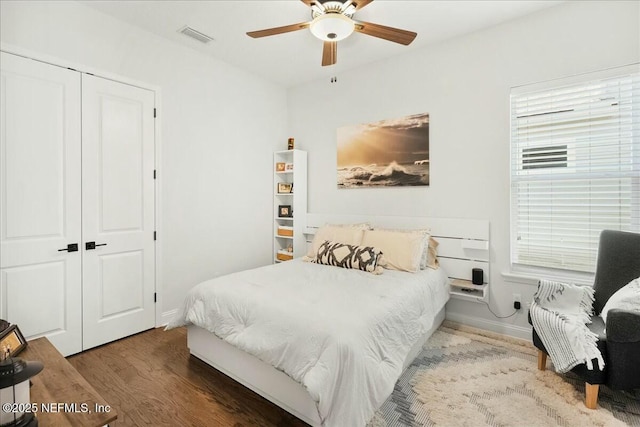 bedroom with a closet, visible vents, ceiling fan, and wood finished floors