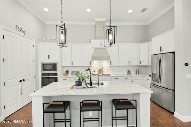 kitchen with dark wood-style floors, white cabinets, appliances with stainless steel finishes, and a breakfast bar area