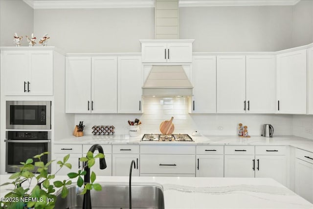 kitchen featuring white cabinetry, decorative backsplash, premium range hood, and stainless steel appliances