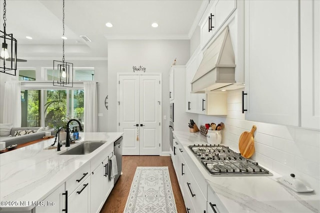 kitchen with appliances with stainless steel finishes, crown molding, custom range hood, and a sink