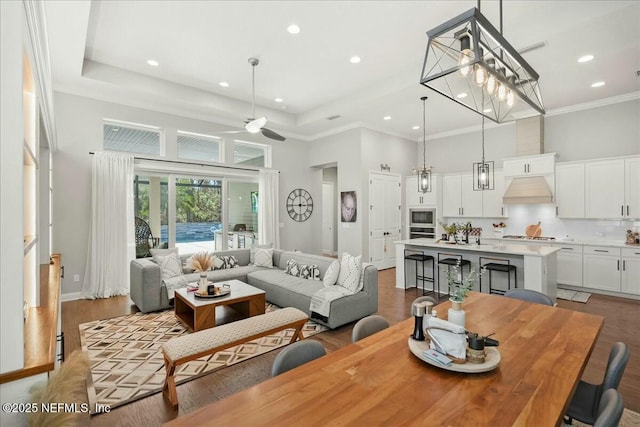 living area with recessed lighting, a tray ceiling, a towering ceiling, and ornamental molding