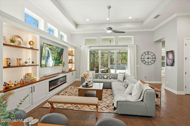 living room featuring a glass covered fireplace, a healthy amount of sunlight, dark wood-type flooring, and ceiling fan