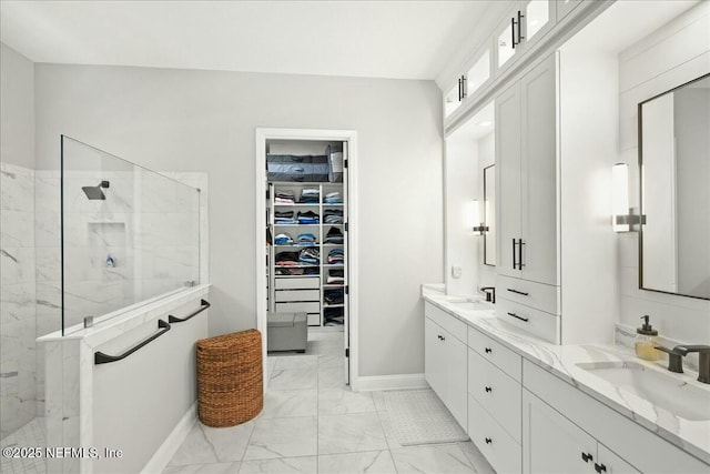 bathroom featuring a sink, a marble finish shower, marble finish floor, and a walk in closet