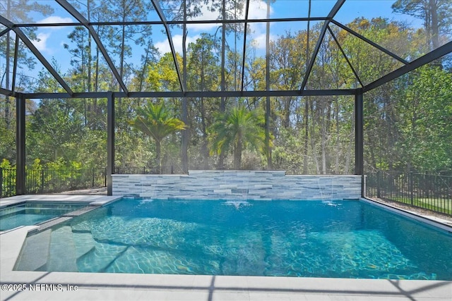 view of swimming pool with glass enclosure, fence, and a pool with connected hot tub