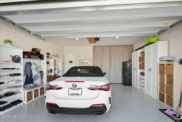 garage featuring a garage door opener and freestanding refrigerator