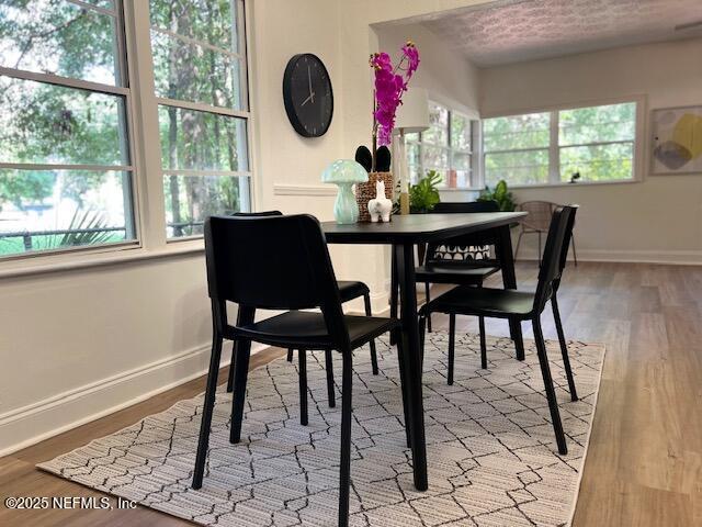 dining space featuring wood finished floors, baseboards, and a textured ceiling