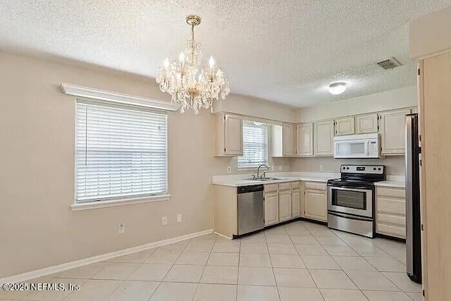 kitchen with baseboards, a chandelier, light countertops, appliances with stainless steel finishes, and a sink