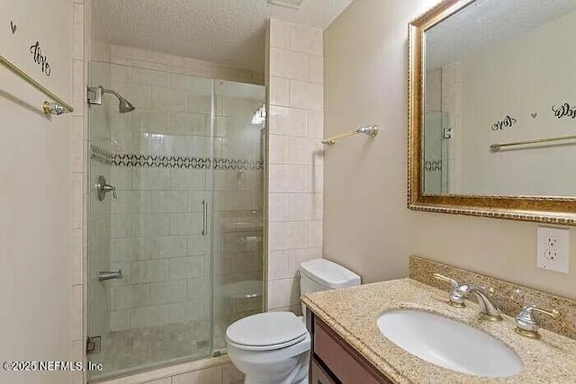 full bathroom with a textured ceiling, a stall shower, vanity, and toilet