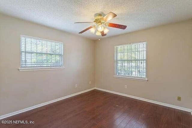 spare room with a wealth of natural light, baseboards, wood finished floors, and ceiling fan