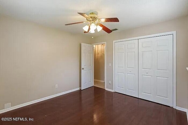 unfurnished bedroom featuring a ceiling fan, wood finished floors, baseboards, and a closet