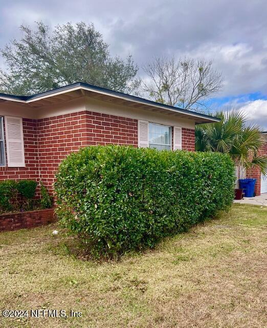 view of side of home featuring a lawn and brick siding