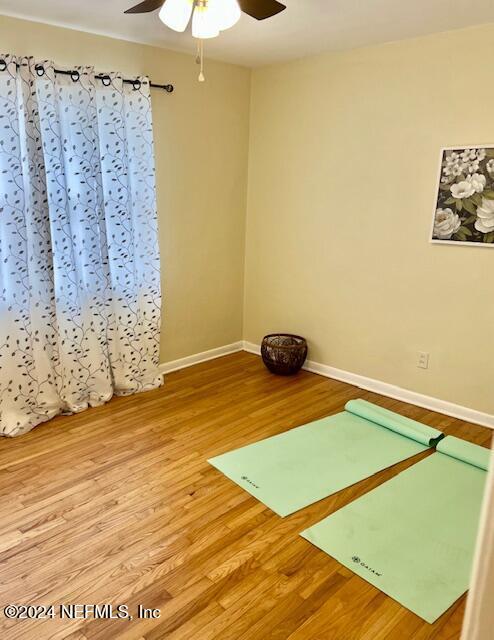 exercise area with wood finished floors, baseboards, and ceiling fan