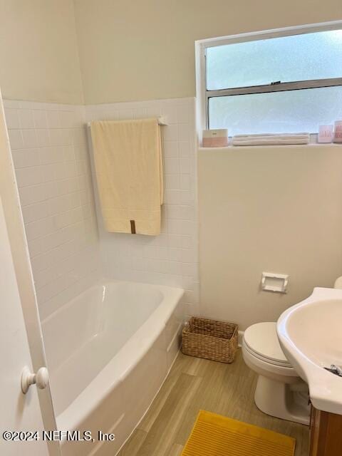 full bath with a bathing tub, toilet, wood finished floors, and vanity