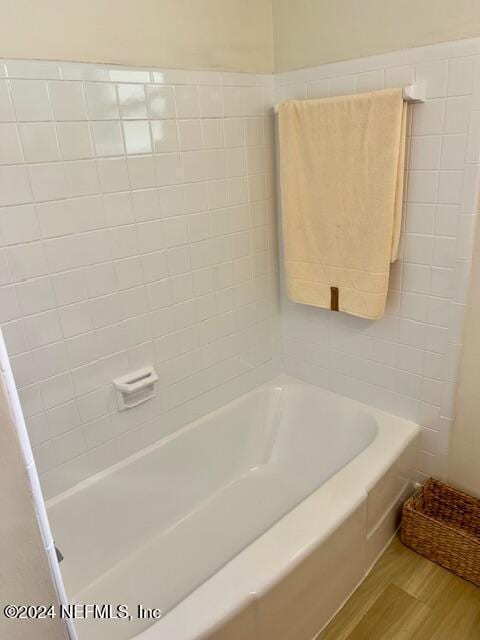 full bathroom featuring wood finished floors and a bath