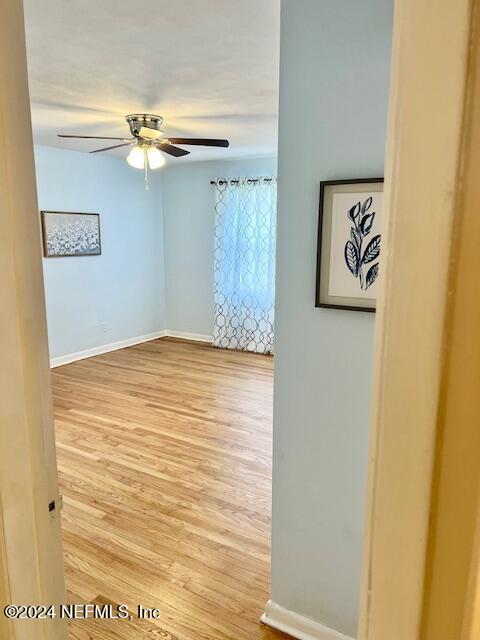 empty room featuring a ceiling fan, wood finished floors, and baseboards