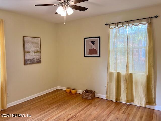 empty room featuring light wood-style flooring, baseboards, and ceiling fan