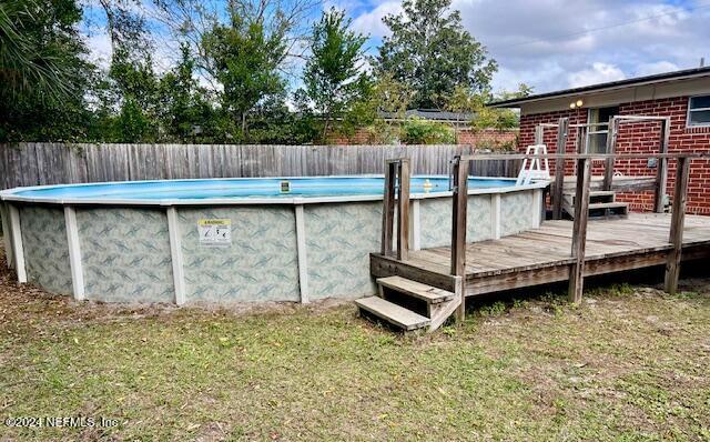 view of pool featuring a yard, a fenced in pool, a deck, and fence