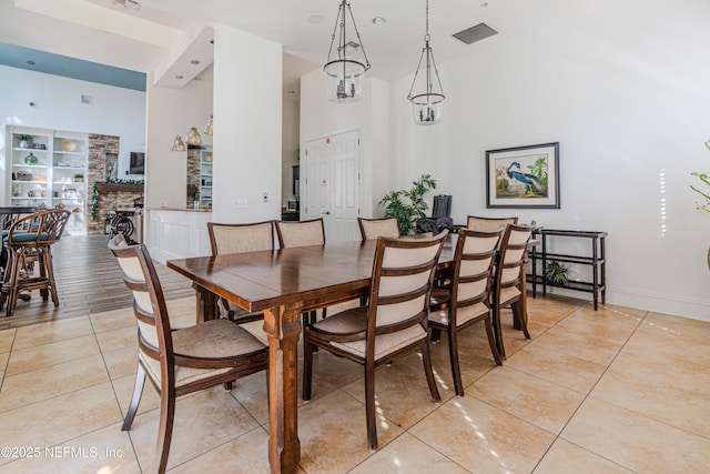 dining room with light tile patterned floors, visible vents, baseboards, and a towering ceiling