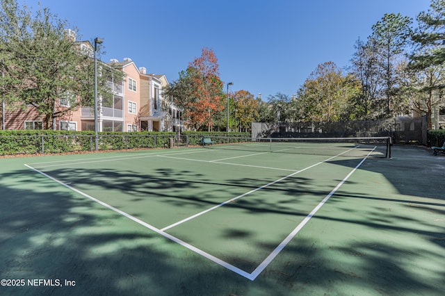 view of tennis court with community basketball court and fence