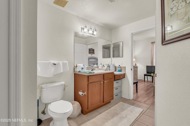 bathroom with vanity, baseboards, visible vents, tile patterned floors, and toilet