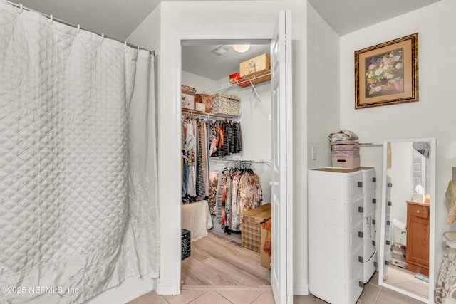 full bath with a walk in closet, tile patterned flooring, and washing machine and clothes dryer