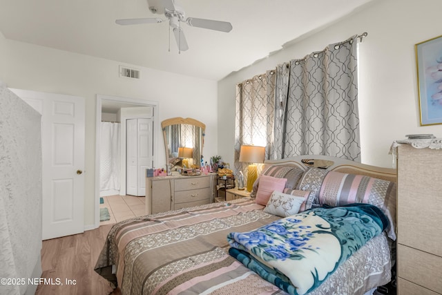 bedroom with a ceiling fan, wood finished floors, and visible vents