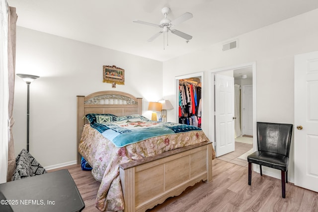 bedroom featuring light wood-type flooring, visible vents, a closet, and a walk in closet