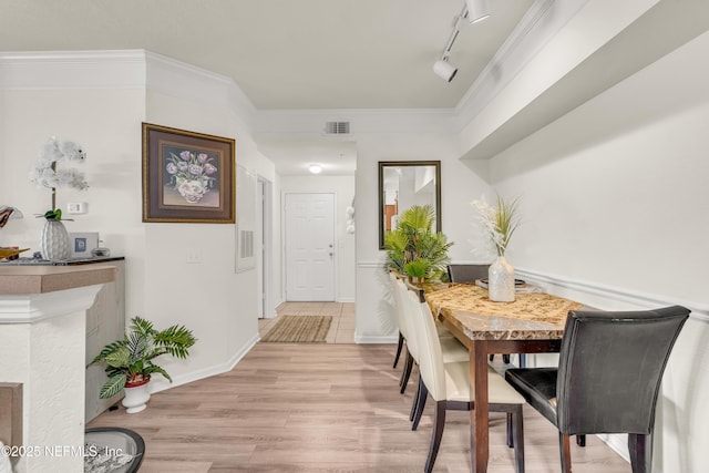 dining area with visible vents, track lighting, crown molding, baseboards, and light wood-style flooring