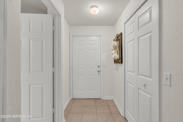 doorway to outside featuring baseboards and light tile patterned flooring