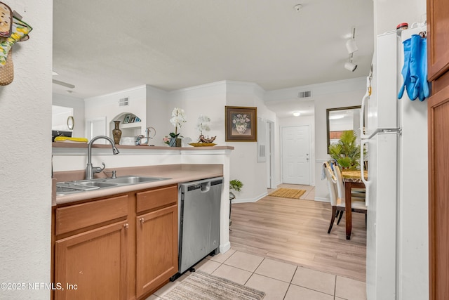 kitchen featuring light tile patterned floors, freestanding refrigerator, a sink, light countertops, and stainless steel dishwasher