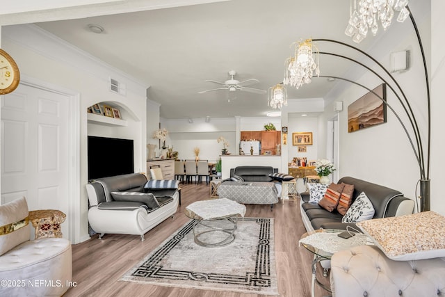 living room featuring ceiling fan with notable chandelier, crown molding, and wood finished floors