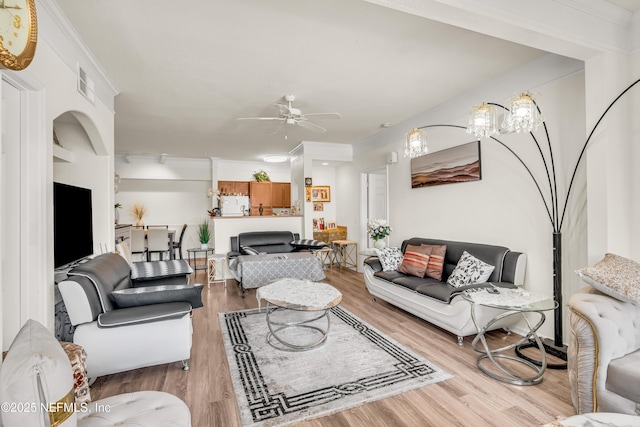 living room with visible vents, wood finished floors, ceiling fan, and ornamental molding