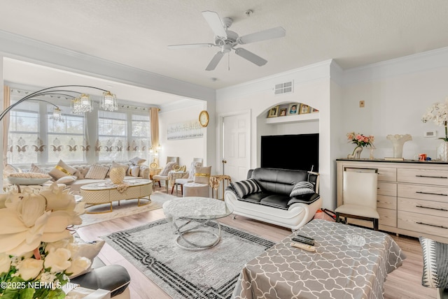 living area featuring ceiling fan, wood finished floors, visible vents, and ornamental molding