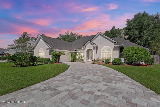 2619 Wrightson Dr, Jacksonville, FL 32223 - ranch-style house featuring stucco siding, a yard, a garage, and decorative driveway