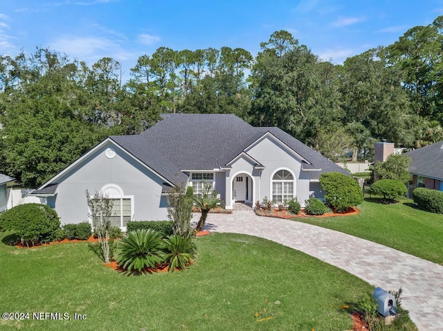 2619 Wrightson Dr, Jacksonville, FL 32223 - ranch-style home with a shingled roof, a front yard, stucco siding, and curved driveway