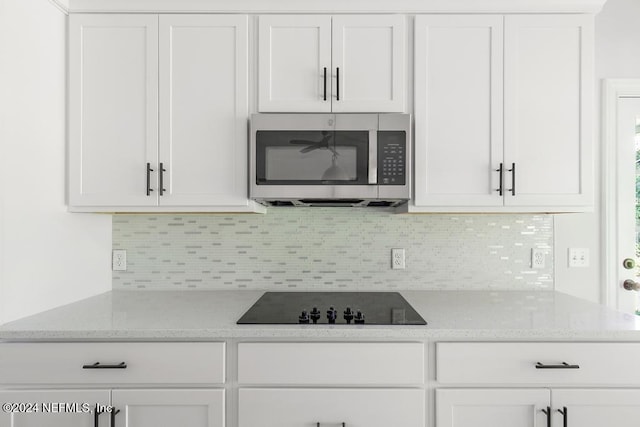 2619 Wrightson Dr, Jacksonville, FL 32223 - kitchen with white cabinets, black electric cooktop, backsplash, and stainless steel microwave