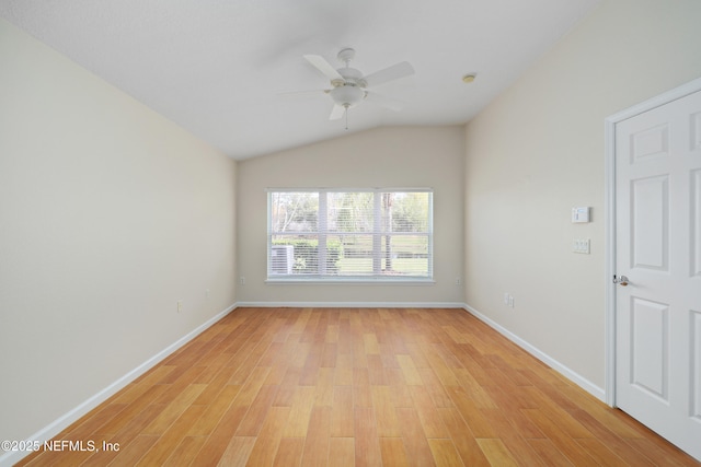 spare room featuring vaulted ceiling, baseboards, light wood finished floors, and ceiling fan